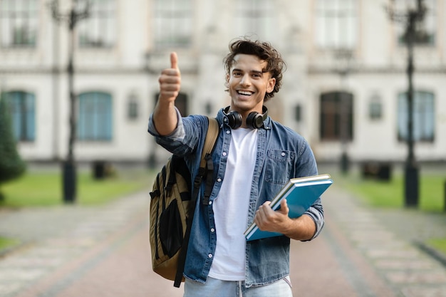 portrait-handsome-student-guy-showing-thumb-up-while-standing-outdoors_116547-72283