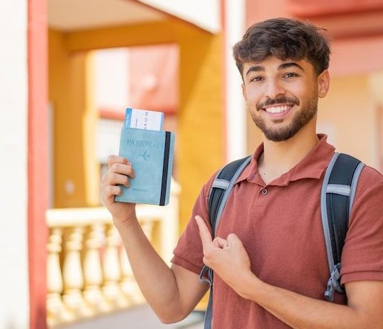 young-arabian-handsome-man-holding-passport-outdoors-pointing-it_1368-505744